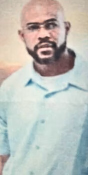 A man with a bald head, glasses, and a beard, wearing a light blue shirt.