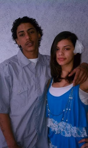 Carlos and a woman posing together against a textured wall.
