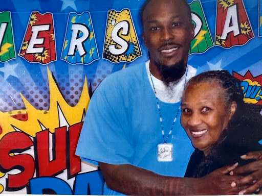 A man and woman smiling together in front of a colorful 'JASPER' banner.