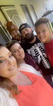 A group of four people, Ronald and three others, posing for a selfie on a porch.