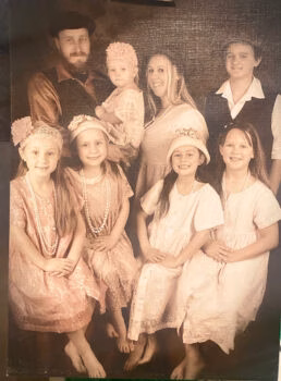 A family portrait of Ronald and his wife with their six children, all dressed in formal attire, posing together.