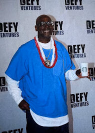 Jonathan, 43, smiles while holding a Starbucks cup at an event with Defy Ventures branding.