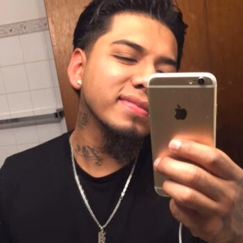 Marcos, 28, taking a selfie in a mirror with a gold iPhone.