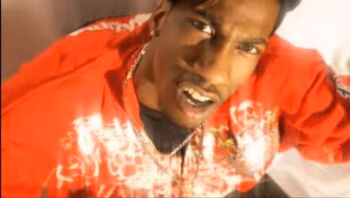 image8 Rodney, 36, wearing a red patterned jacket and a chain, looks intensely at the camera.