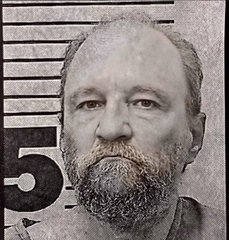 A black and white mugshot of a man with a beard, attached to a height chart.