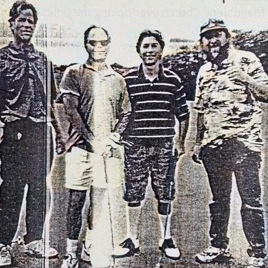 Four men standing together outdoors in a group photo.