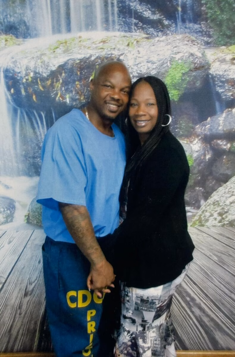 A man and a woman posing together in front of a waterfall backdrop.