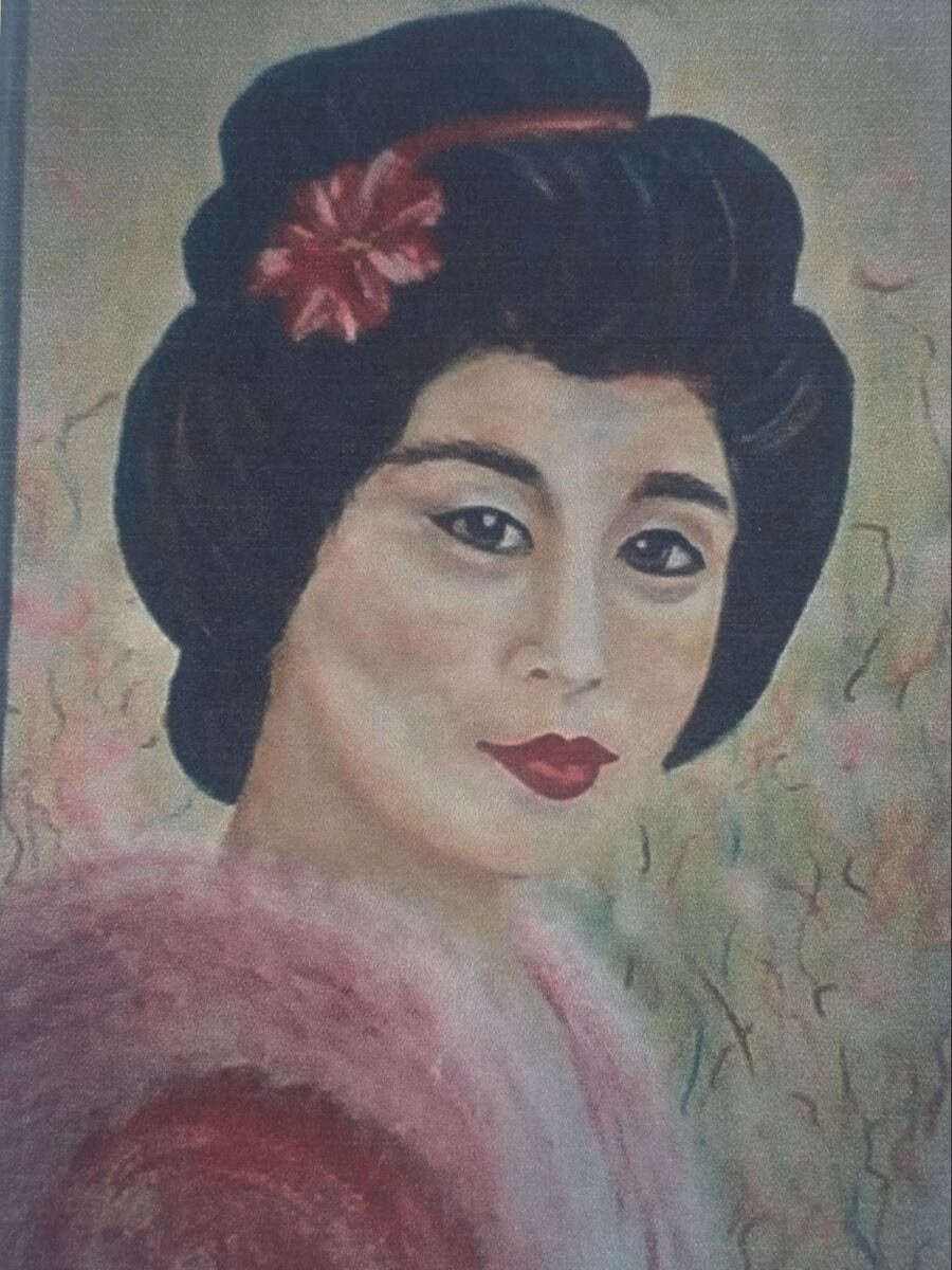 Portrait of a woman with a traditional black updo adorned with a red flower, wearing a pink garment against a soft, textured background.