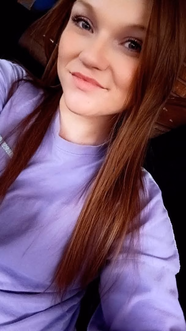 Miranda, 30, smiling with long red hair and a purple shirt.