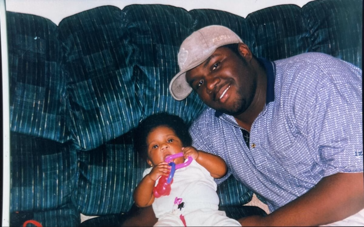 A man and a baby sitting together on a green couch.