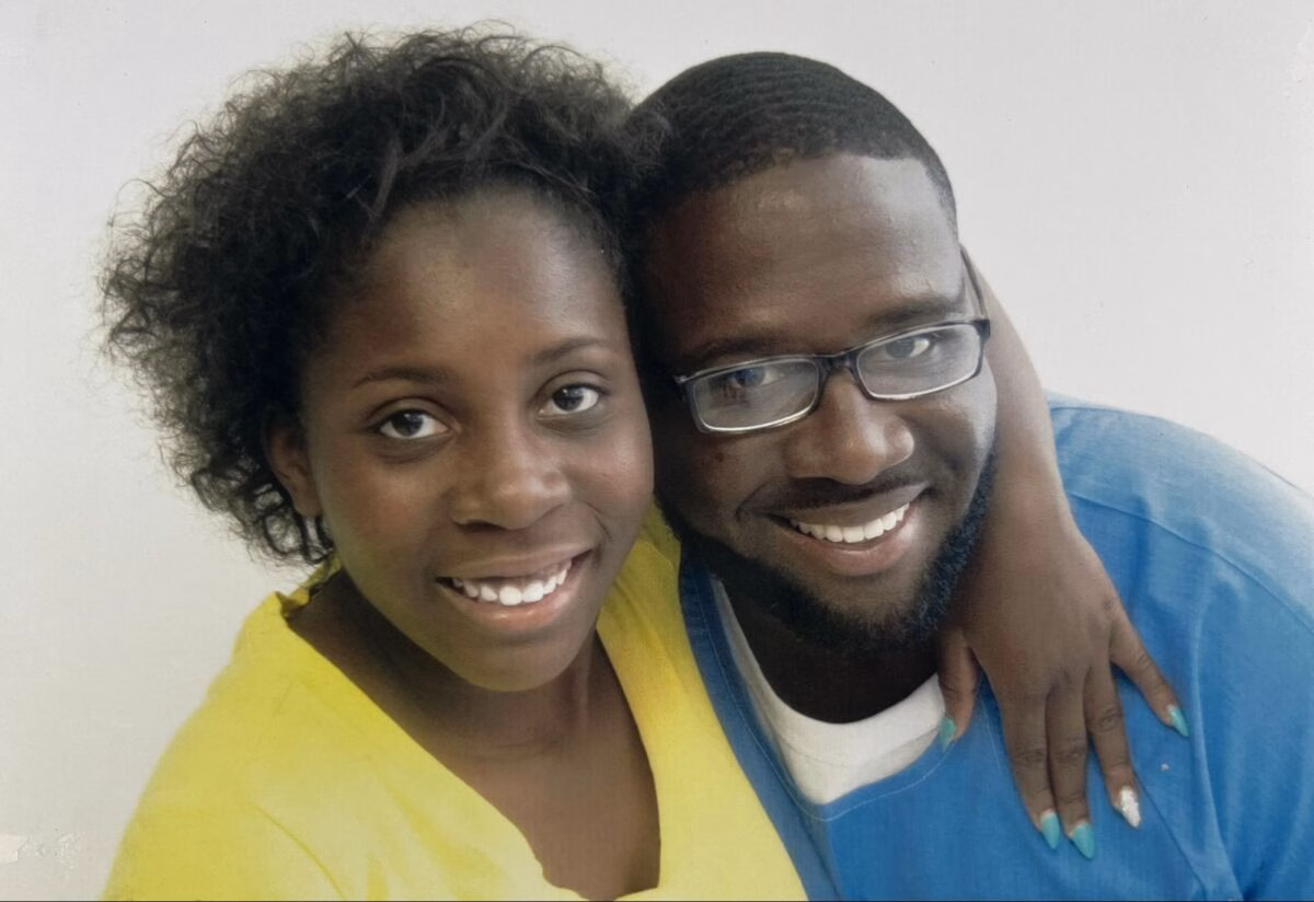 A smiling couple, Bill and his partner, posing closely together against a plain background.