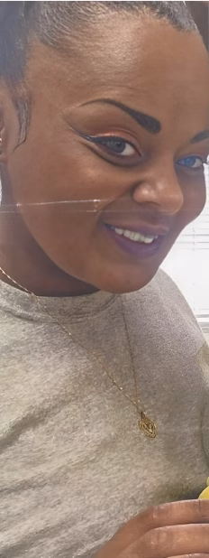 Close-up portrait of Niesha, 41, smiling with dark eyeliner and a gold necklace.