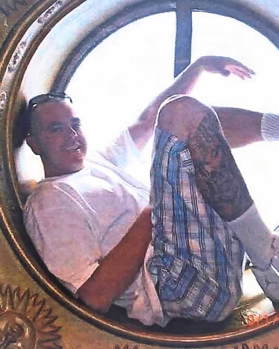 2 A man with tattoos on his arm and sunglasses on his head, smiling and looking towards the camera.