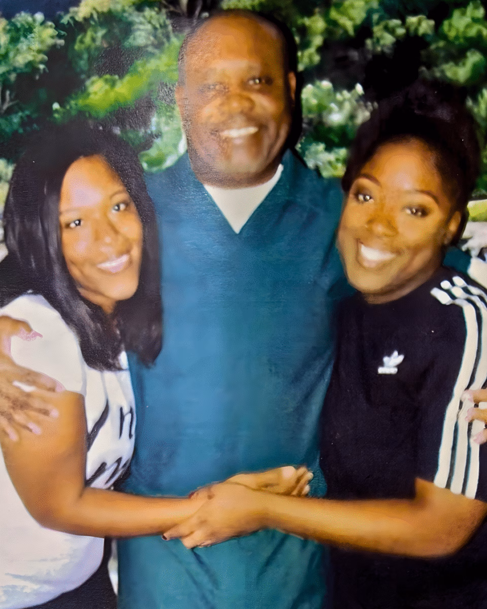 5 A smiling man in a teal shirt stands between two women, all posing together outdoors.