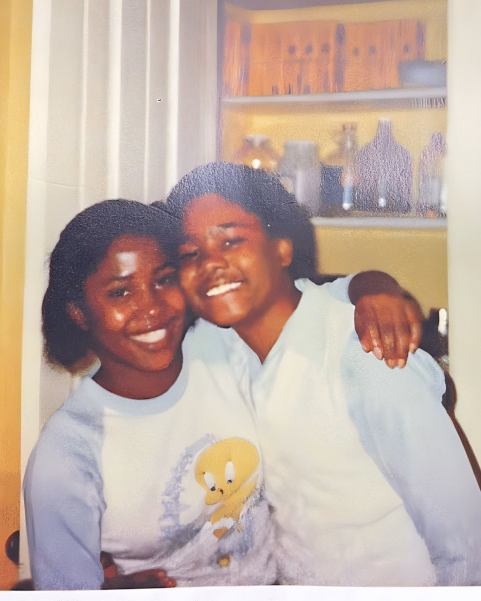 7 Two young women with dark curly hair smiling and embracing in a home setting.