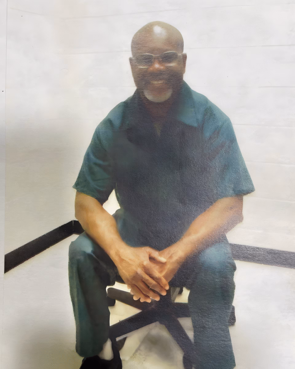 9 Charles, 56, a bald man with glasses and a white beard, smiling while seated on a chair.