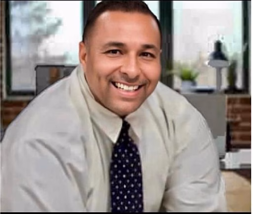 Jose1 smiling in a light-colored shirt and dark polka-dot tie, set against a blurred office background.