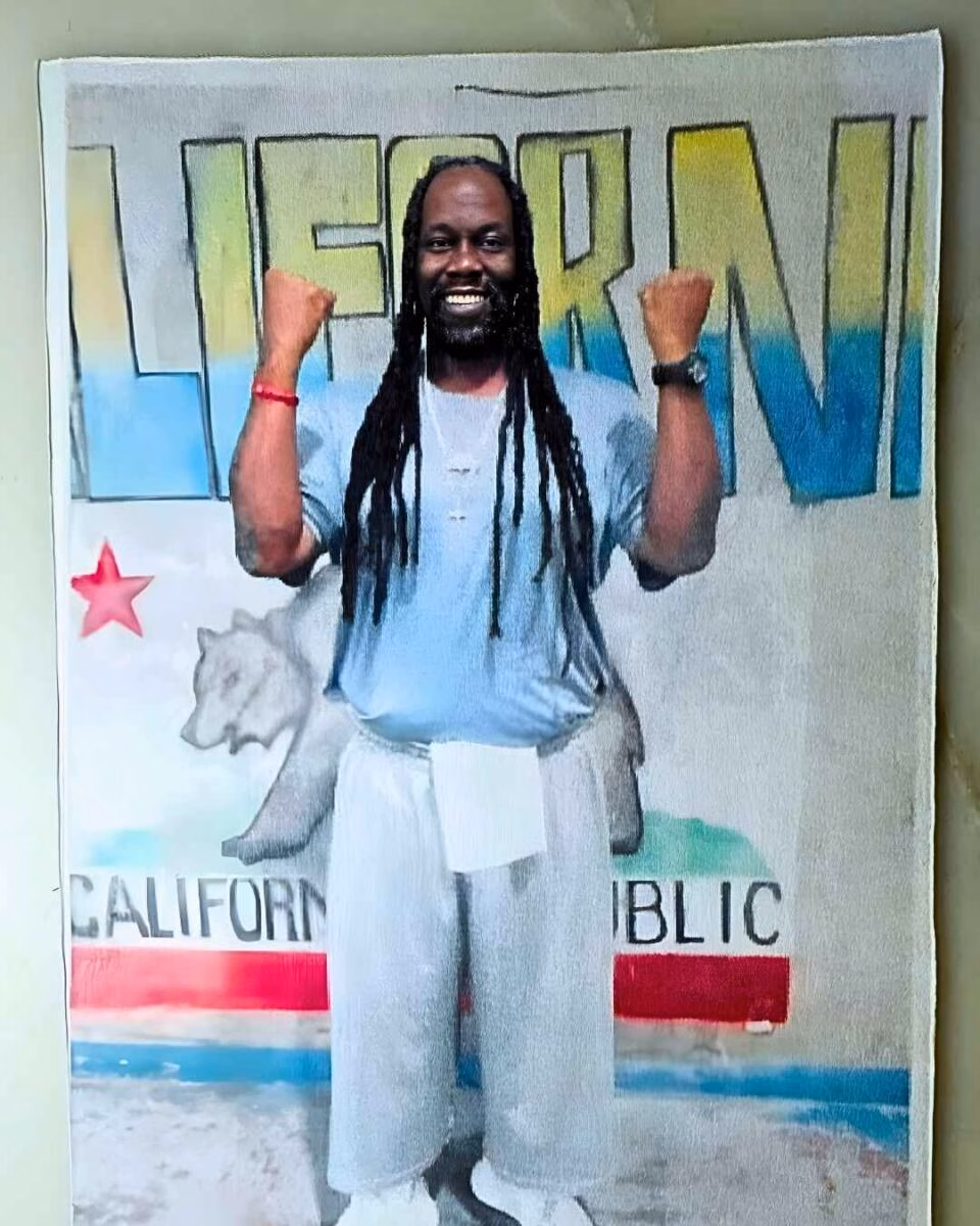 Albert Jones stands in front of a California flag backdrop with the name 'LIEBMAN' above him, smiling with both fists raised.