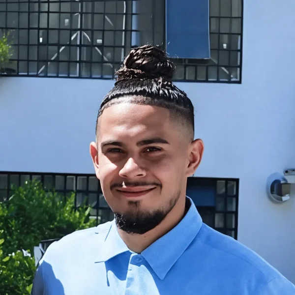 Our Team 24 Edwin, a man with a top knot and goatee, smiles in a blue and white shirt.