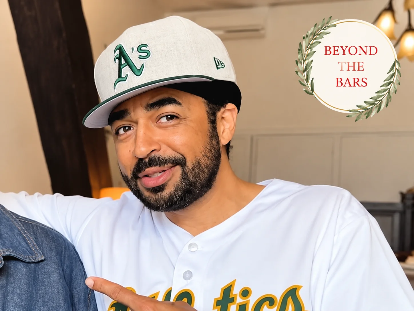 Larry White wearing a white Oakland Athletics baseball cap and jersey, pointing towards the camera.