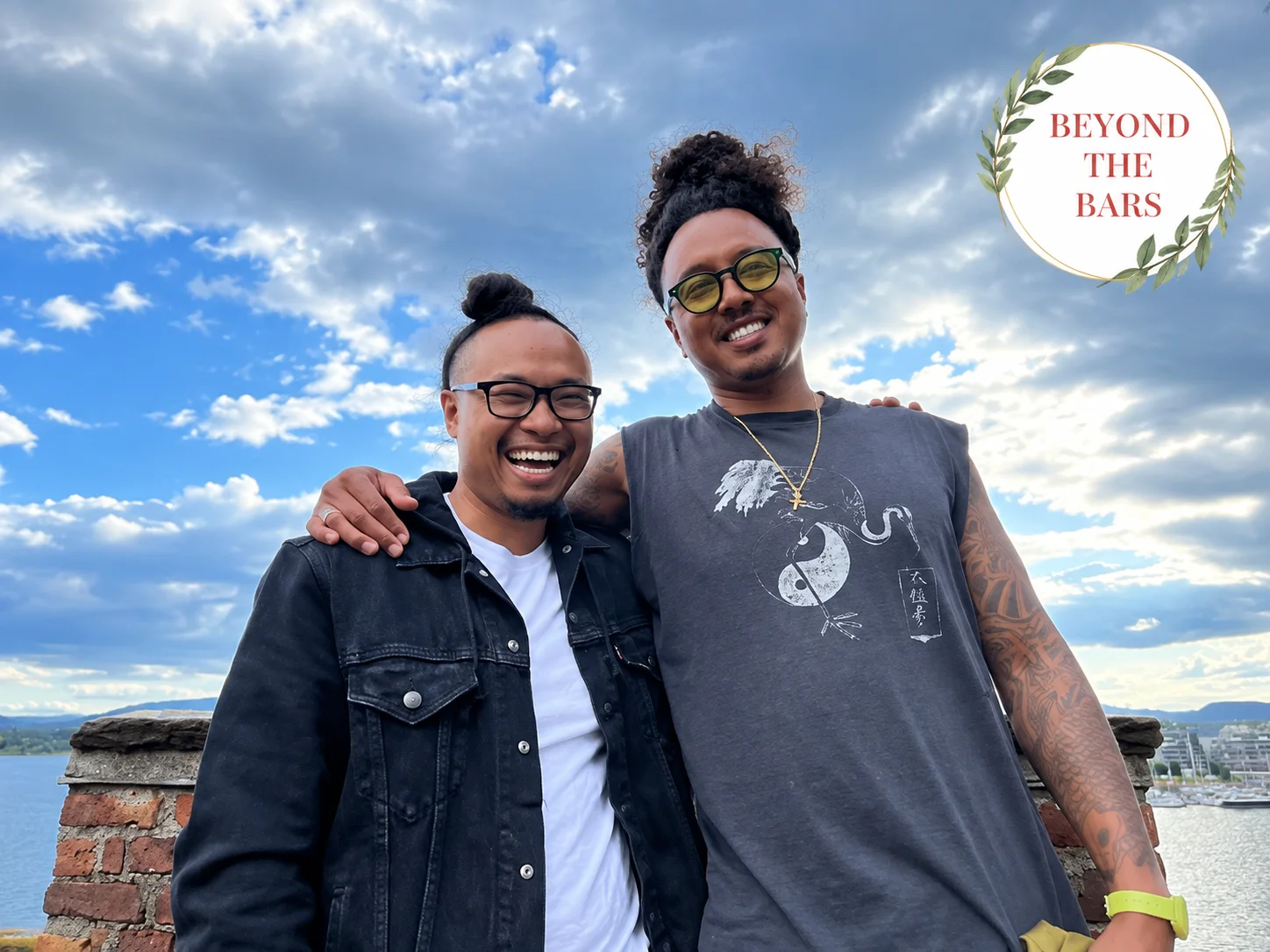 Thanh and a friend smiling together outdoors under a cloudy sky.