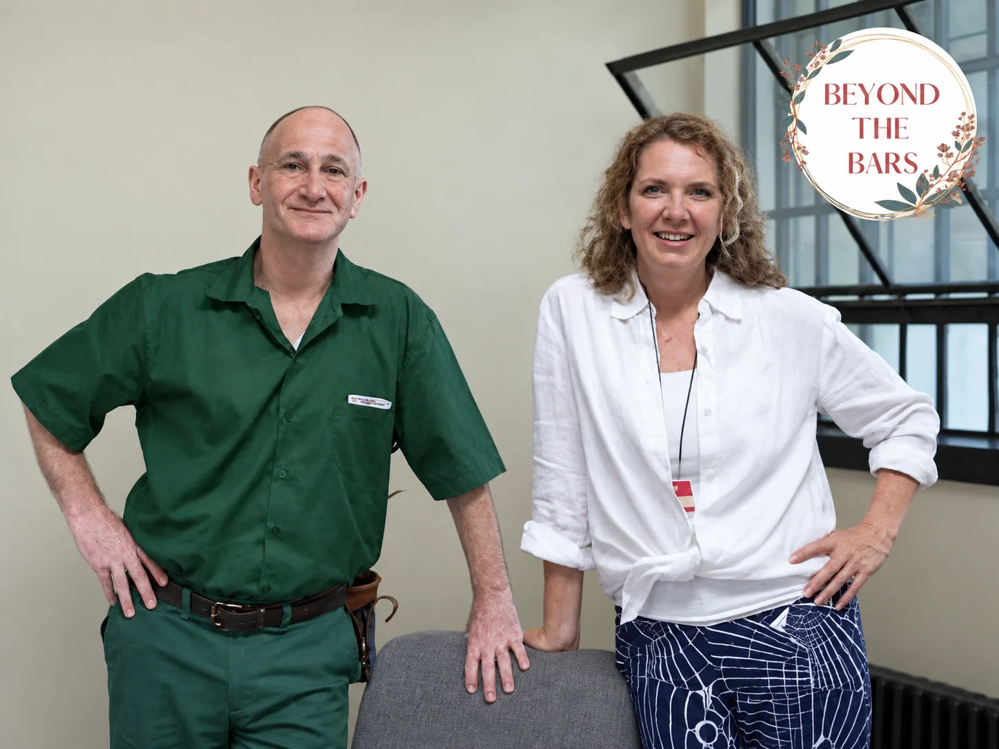 Eric, a man in a green uniform, and a woman in a white shirt stand together in a room with a barred window.
