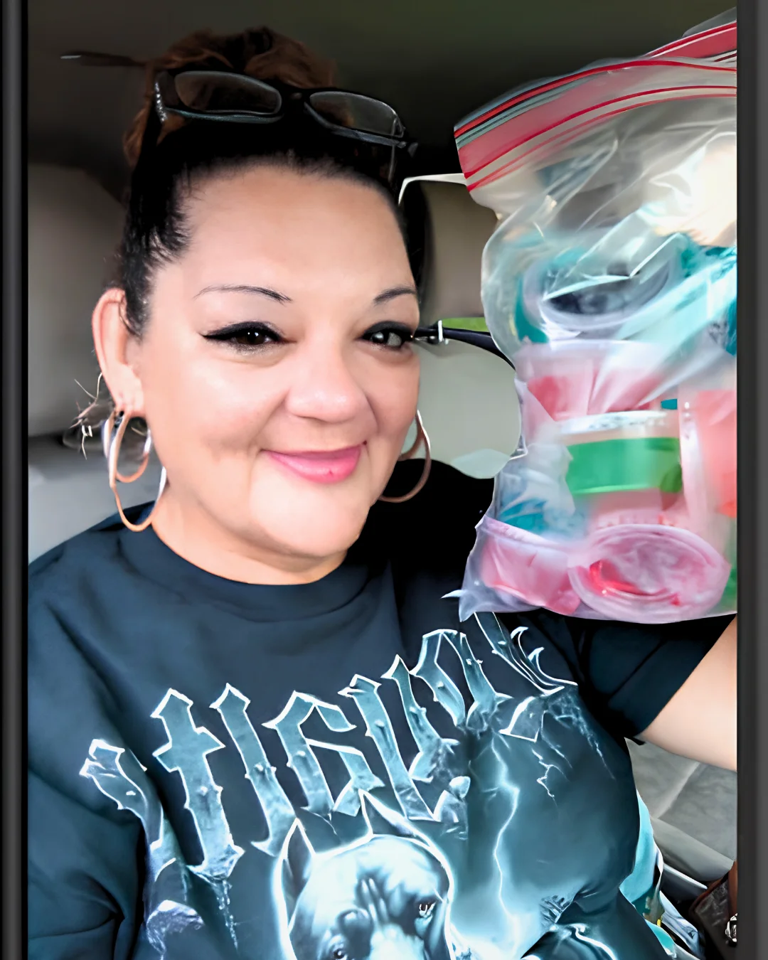 Estefana smiling while holding a clear bag of personal belongings in a vehicle, featured in her Humans of San Quentin story.